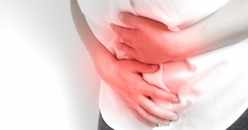 お腹に手を当てて痛がる女性