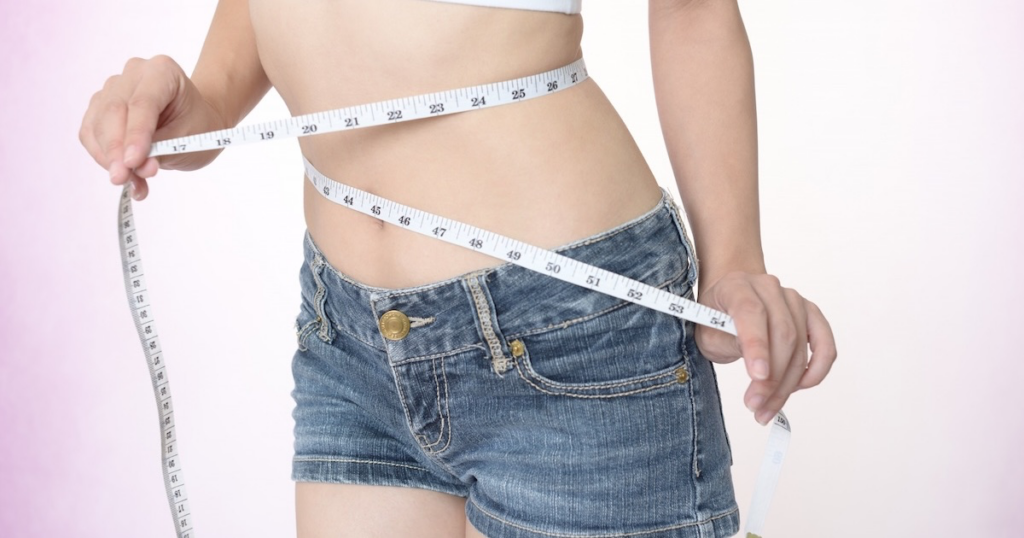 痩せている女性がお腹にメジャーを巻き付けている画像