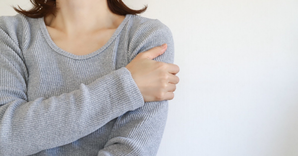 自分の腕に触れる女性