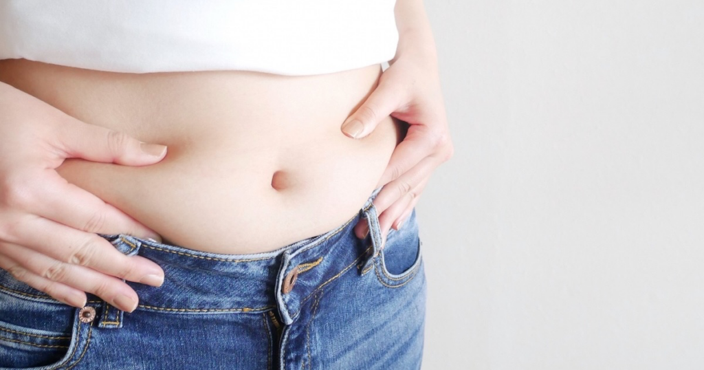 お腹をつまむ女性